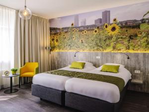 a hotel room with a bed and a mural of sunflowers at ibis Styles Almere in Almere