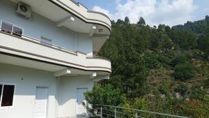 a white building with a hill in the background at At Home in Swat