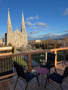 a balcony with chairs and a table and a church at Appartement Le Yin in Sainte-Anne-de-Beaupré