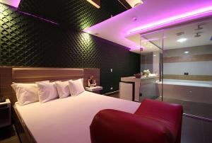 a bedroom with a large bed and a red chair at Le Nid Motel in Sao Paulo