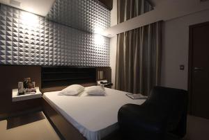 a bedroom with a white bed and a black chair at Le Nid Motel in Sao Paulo