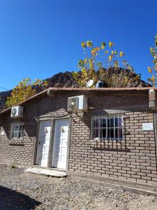 Un edificio de ladrillo con dos ventanas y flores en el techo. en Cabañas Cumbre, en La Porteña