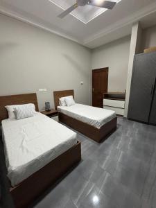 une chambre avec deux lits et un ventilateur de plafond dans l'établissement Explore Afreeka Serviced Apartments Abia Beach, à Trofwi
