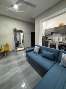 un salon avec un canapé bleu et une cuisine dans l'établissement Explore Afreeka Serviced Apartments Abia Beach, à Trofwi