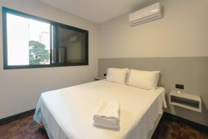 a bedroom with a large white bed with a window at Conforto e Localização TOP - MJ41 in Maringá +16 photos