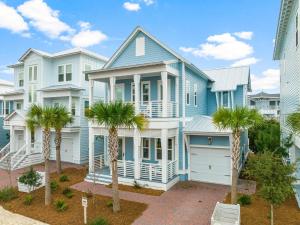 a blue house with palm trees in front of it at Cottage by the Sea in Watersound Beach