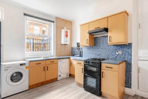 a kitchen with wooden cabinets and a washer and dryer at Burley Guest House in Headingley