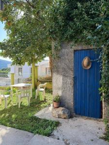 eine blaue Tür mit einem Hut darauf neben einem Tisch in der Unterkunft Villa Maria in Ðenovići