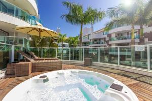 a hot tub on a deck next to a building at Boulevard 110-B - Excelente apartamento em condomínio de luxo no centro de Bombinhas - Piscina - Jacuzzi - Academia - Portaria 24h. in Bombinhas