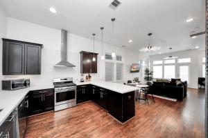 a kitchen and living room with wooden floors and appliances at AMAZING ROOFTOP! DOWNTOWN SKYLINE VIEWS!!! SLEEPS 15 in Houston