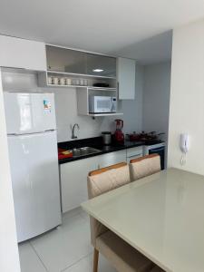 Una cocina con electrodomésticos blancos y una mesa con sillas. en Lindo apartamento na zona sul de Ilhéus, en Ilhéus