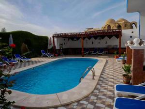 a swimming pool in a yard with chairs and a building at Villa Quiet Place in Luxor