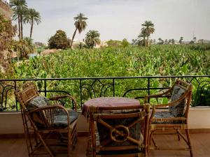 a balcony with a table and chairs and a field of corn at Villa Quiet Place in Luxor