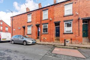 a car parked in front of a brick building at Burley Guest House in Headingley