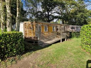 a wooden cabin in a yard next to some trees at MH3-Confort, 3ch, 6 pl, 2 FUN-PASS OFFERT dès 5 nuits, LAVE VAISSELLE, TV, WI-FI, Draps fournis et ménage, en option ! in Pont-Aven