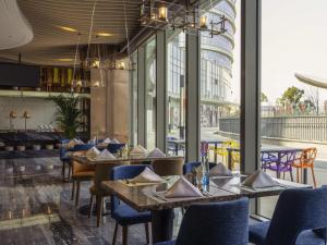 鄭州市にあるNovotel Zhengzhou Airportのテーブルと椅子と大きな窓のあるレストラン