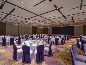 鄭州市にあるNovotel Zhengzhou Airportの白いテーブルと椅子が置かれた宴会場 +100枚の写真