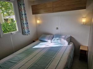 a small bedroom with a bed and a window at MH3-Confort, 3ch, 6 pl, 2 FUN-PASS OFFERT dès 5 nuits, LAVE VAISSELLE, TV, WI-FI, Draps fournis et ménage, en option ! in Pont-Aven +10 photos