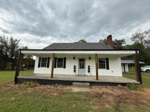 a small white house with a porch on a field at Juanitas Garden Cottage in Jonesville