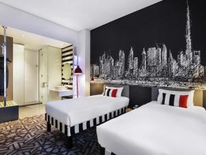 a hotel room with two beds and a black wall at ibis Styles Dubai Airport Hotel in Dubai +32 photos