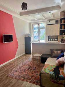 a living room with a couch and a red wall at Bright 1BR flat in the city centre Tsereteli ave in Tbilisi City