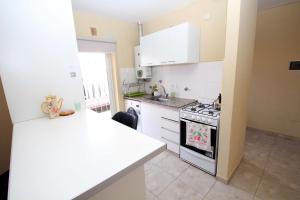 Una cocina con gabinetes blancos y un horno de estufa. en Casa cómoda y espaciosa con pileta, en San Salvador de Jujuy