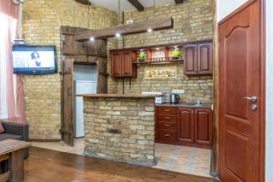 a kitchen with wooden cabinets and a stone wall at Baroque-Style Apartment in the Heart of Kyiv in Kyiv +17 photos