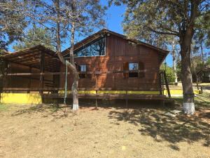 a log cabin with trees in front of it at Chalé frente para o lago - Camping Carrion in Itu