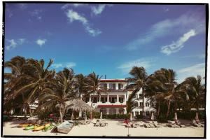 a hotel on a beach with palm trees and a building at Casa Altamar in Tulum