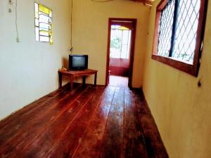 an empty room with a television and a wooden floor at Pousada Sol e praia in Manaus
