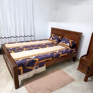 a bed with a wooden frame in a room at Solara Holiday Homes in Anuradhapura +2 photos