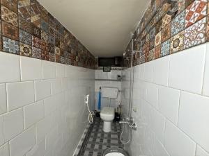a small bathroom with a toilet and tiled walls at 2BHK Home fully furnished at Sahid Nagar near INOX in Bhubaneshwar