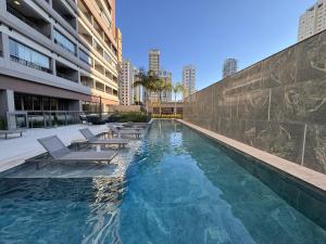 ein Swimmingpool mit Liegestühlen und ein Gebäude in der Unterkunft Flat em Moema Grand Vitrali - Aero Congonhas in São Paulo