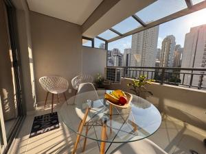 Zimmer mit einem Glastisch und Stühlen auf dem Balkon in der Unterkunft Flat em Moema Grand Vitrali - Aero Congonhas in São Paulo