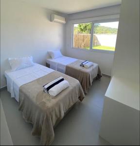 Dos camas en una habitación con ventana. en Buzios Heven, en Búzios