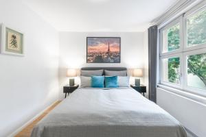 Un dormitorio blanco con una cama grande con almohadas azules. en Lofty Torstr Apartments, 4 unique units from 1-3 bedrooms in Mitte, ideal for families & groups, from 2 up to 8 Guests, en Berlín