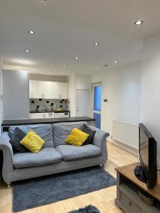 a living room with a gray couch and yellow pillows at Unique 3 Bed Flat and Cinema Room in Rogerstone