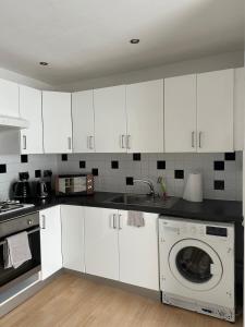 a kitchen with white cabinets and a dishwasher at Modern and Cosy 3 bedroom flat in newport, great M4 Links in Rogerstone +15 photos