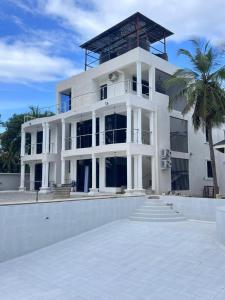 a white building with a palm tree in front of it at Serian Breeze Villa in Ukunda
