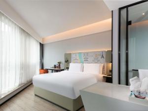 a hotel room with a white bed and a desk at Mercure Chengdu Xindu in Chengdu