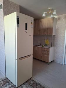 a kitchen with a white refrigerator in a room at Квартира in Tridtsatʼ Let Kazakhstana