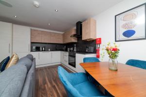 a kitchen and living room with a table and blue chairs at LUSH 2 Bed Central Apartment Hull Centre in Hull +25 photos