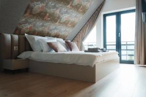 a bedroom with a bed with a painting on the wall at Domki Osada Klenina SAUNA & BALIA in Kamienica