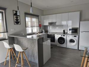 a kitchen with white cabinets and white appliances at Cantinho do alto in Porto Judeu