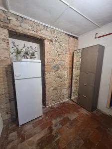 a white refrigerator in a room with a brick wall at La Corte del Tadde in Lammari