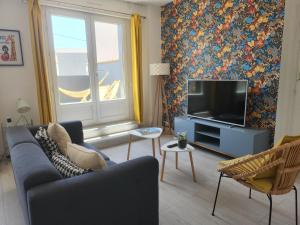 Una sala de estar con un sofá y un televisor de pantalla plana. en Le Cocon Marin, en Saint-Georges-de-Didonne