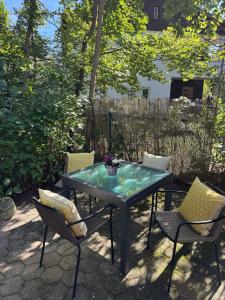 a patio table with chairs and a table with a glass top at 30 min from Munich & S-Bahn apartment with garden in Gauting