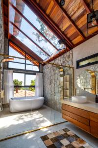 a bathroom with a tub and a large window at Pousada Cerejeiras in Monte Verde