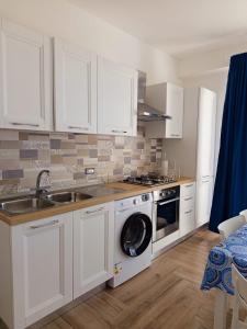 a kitchen with white cabinets and a washing machine at Solleone - Appartamento 9C in Paestum