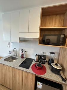 Una cocina con estufa, fregadero y microondas. en Vista Skyline en Piso 13 - Entre Lince y San Isidro, en Lima